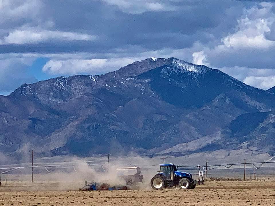 Farm equipment operating in a field below the Nevada mountains